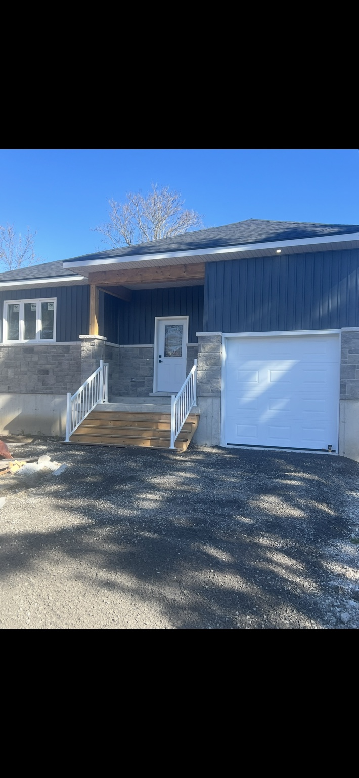 Bungalow with dark siding, stone base, timber porch and white garage door