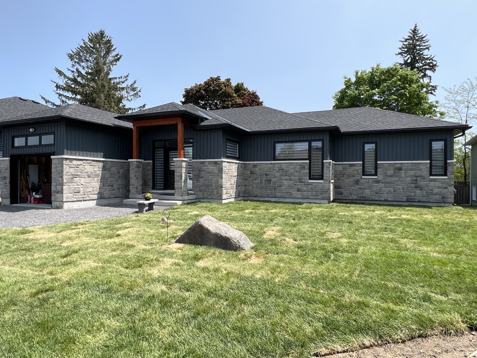 Contemporary bungalow with stone exterior and dark siding