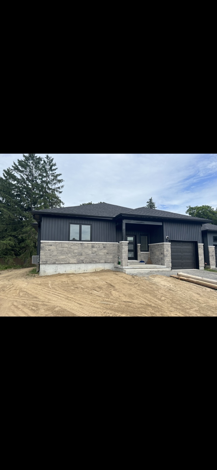Bungalow with dark siding, pale stone front and single garage