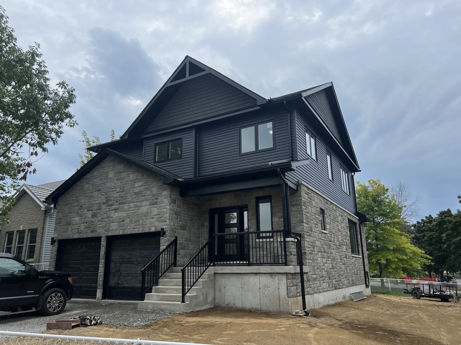 Two-storey home with stone exterior, dark siding and front porch