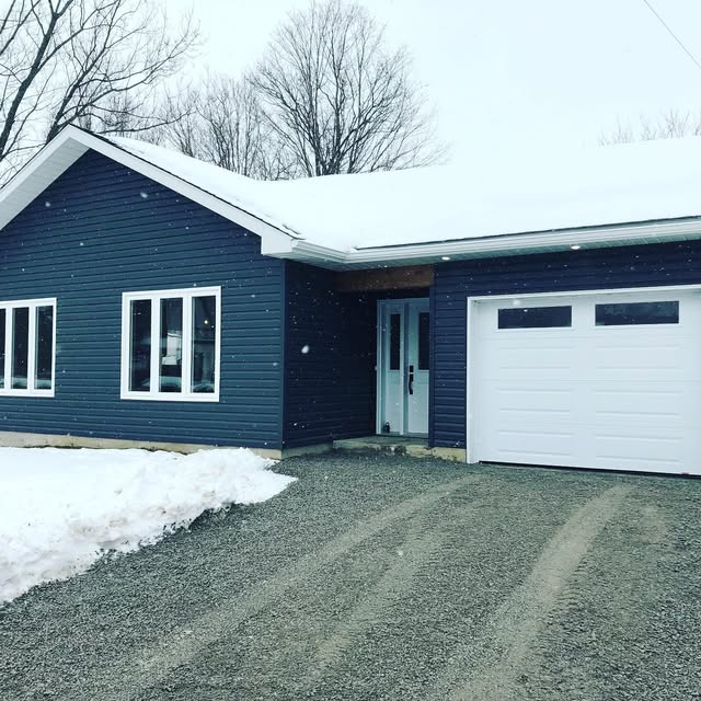 Dark-sided single-storey home with attached garage in winter